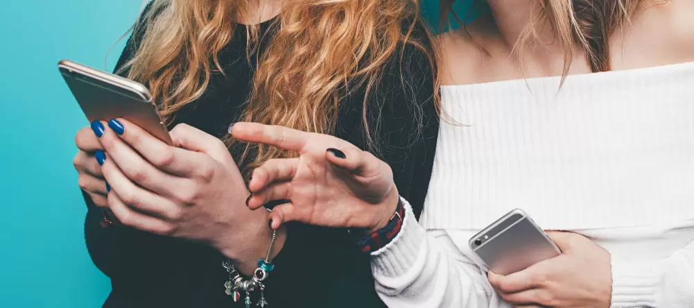Wieso sollte ich eine Leinwand online bestellen? Zwei Frauen benutzen ihre Mobiltelefone.